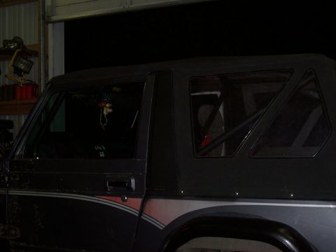1988 Suzuki Samurai - 1988 Suzuki Samurai shown from the side, a black soft top and interior roll cage.