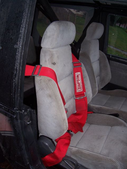 1988 Suzuki Samurai - Interior view of a vehicle with racing seats and a red Simpson harness, roll cage present.