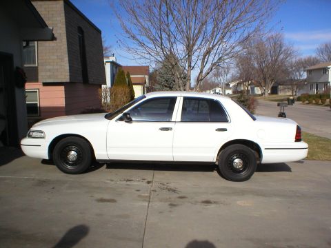2000 Ford Crown Victoria - A white 2000 Ford Crown Victoria sedan is parked in a driveway on a sunny day.