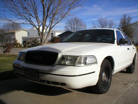 2000 Ford Crown Victoria - A white 2000 Ford Crown Victoria is parked in a residential driveway under a clear blue sky.
