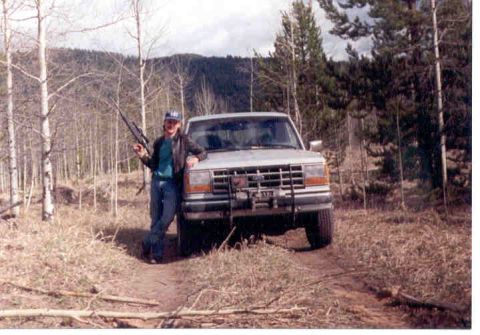 1989 Ford Bronco - Man poses with his 1989 Ford Bronco in a wooded area, holding a rifle.