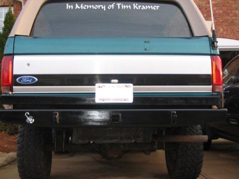 1996 Ford Bronco - The rear of a 1996 Ford Bronco features a custom black bumper with a scorpion decal and a "In Memory of Tim Kramer" sticker on the window.