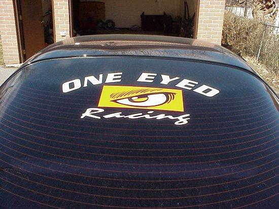"One Eyed Racing" decal with eye logo on dark vehicle rear window