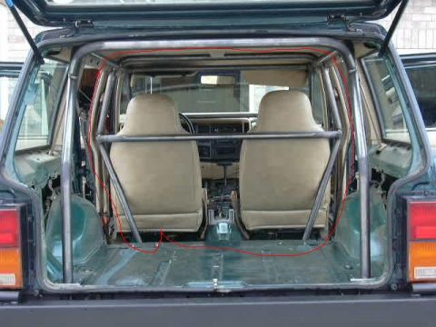 1994 Jeep Cherokee - The interior of a Jeep Cherokee is shown with a prominent custom roll cage structure fitted around the seating area and cargo space.