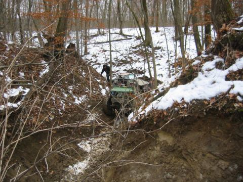 1992 Ford Bronco - An off-road vehicle navigates a challenging muddy and snowy terrain, with another vehicle partially visible in the background.