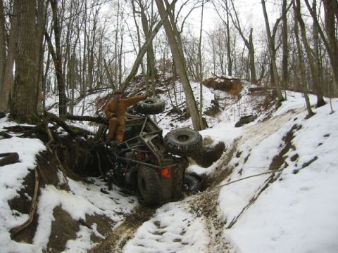 1992 Ford Bronco - Off-road vehicle stuck in a snowy ditch, with a person standing on top of it.