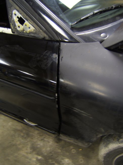 close-up of a black car's door and fender seam, showing bodywork
