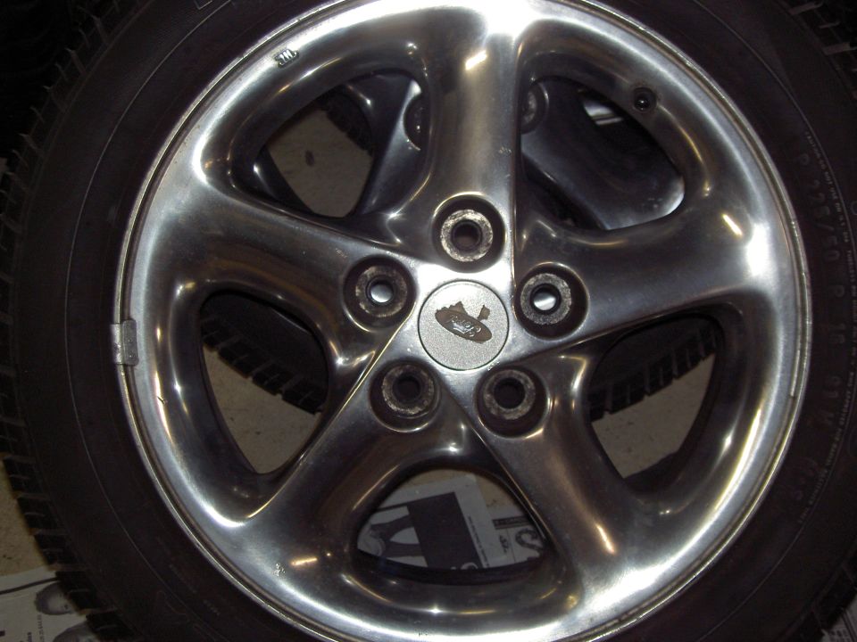 Chrome five-spoke wheel with a small emblem in the center