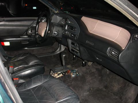 1993 Ford Taurus - The interior of a car shows black leather seats and a dark dashboard with the center console removed.