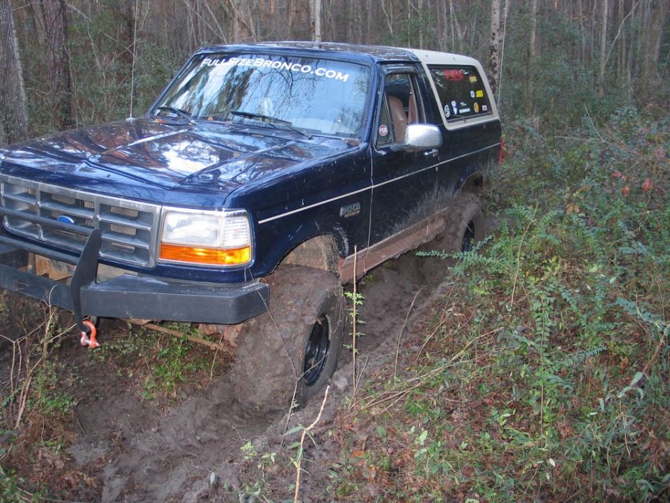 Blue 1995 Ford Bronco stuck in mud, windshield sticker reads "FULLSIZEBRONCO.COM"