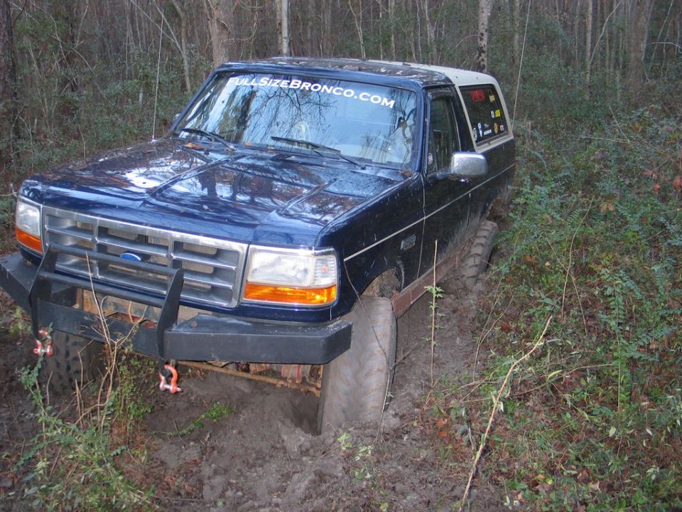 1995 Ford Bronco stuck in mud off-road, front bumper visible with tow hooks