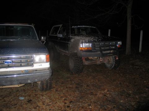 1995 Ford Bronco - A black Ford Bronco is parked next to another vehicle at night.