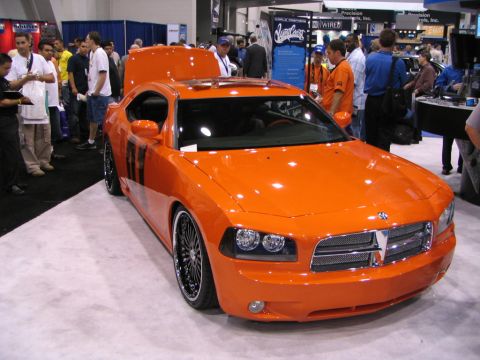 1986 Pontiac Fiero - Orange Dodge Charger with black racing stripes on display at an auto show.