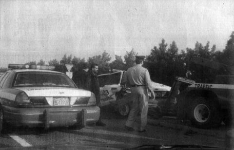 1999 Mercury Grand Marquis - A police car, tow truck, and another vehicle are at a roadside scene, with officers present.