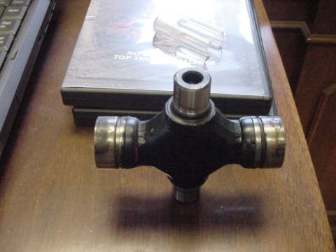 1969 Ford Bronco - A universal joint part is shown on a table next to some DVDs.