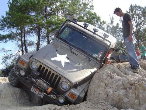 2004 Jeep Wrangler - This Jeep Wrangler is navigating a challenging off-road obstacle with assistance from onlookers.