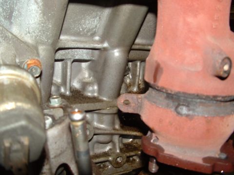 1996 Ford Probe - Close-up view of an engine block and exhaust manifold, showing oil residue and metal components.