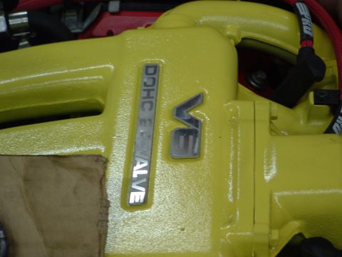 1996 Ford Probe - Close-up of a yellow engine valve cover displaying V6 and DOHC emblems.