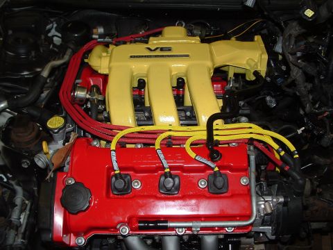 1996 Ford Probe - Close-up of a modified V6 engine bay with bright yellow intake manifold and red valve covers.