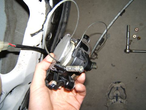 1993 Ford Probe - A car's window regulator mechanism is shown being held by a hand, with associated parts and tools nearby.
