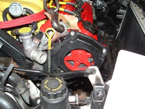 1996 Ford Probe - Close-up view of an engine bay, highlighting red and black engine components and a power steering fluid reservoir.
