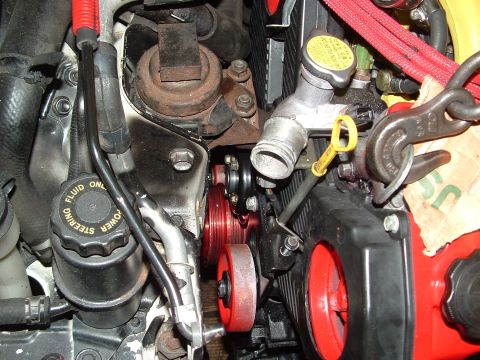 1996 Ford Probe - Close-up of engine components, including red-colored pulleys and fluid reservoirs.