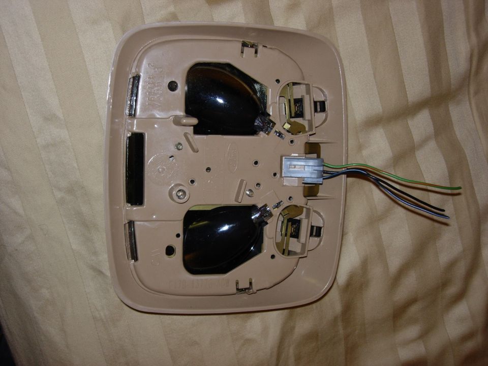 Back side of a tan overhead dome light console showing wiring and white connector plug