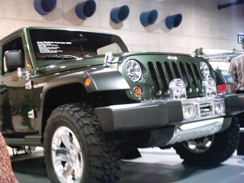 1986 Ford Bronco - A green Jeep Gladiator Concept vehicle is displayed indoors with a prominent chrome grille and off-road tires.