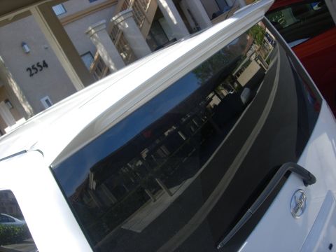 2006 Scion xB - Rear view of a white vehicle showing a spoiler and tinted window with reflections.
