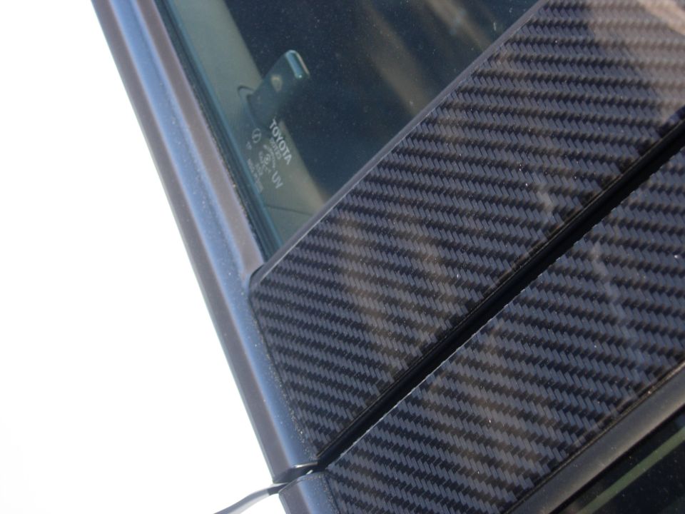 Carbon fiber trim on a car window frame with visible TOYOTA text on the glass