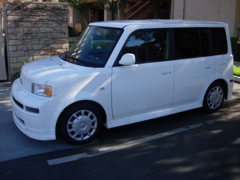 2006 Scion xB - A white 2006 Scion xB is parked in a lot, showing its front three-quarter view with tinted windows and side skirts.