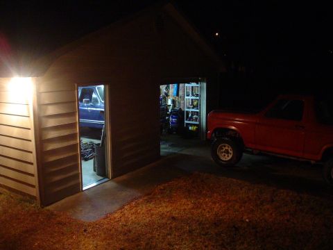 1984 Ford Bronco - Two pickup trucks are visible, one red outside a garage and one blue inside.