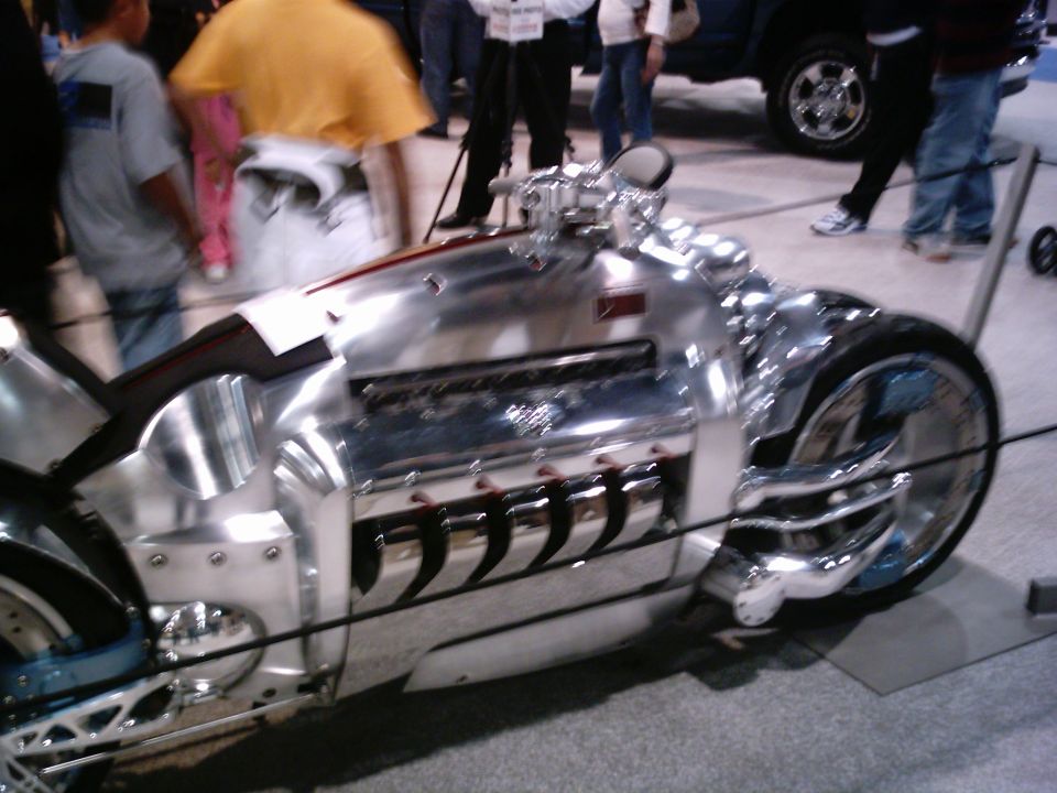 Chrome custom motorcycle with exposed V-engine and unique front wheel