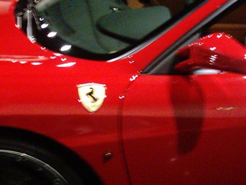 1986 Ford Bronco - Close-up of a red Ferrari emblem on the side of a red car.