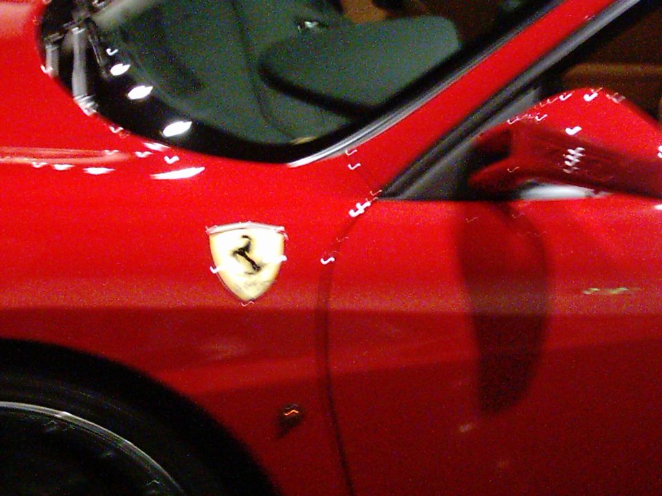 Red Ferrari emblem on a red car door