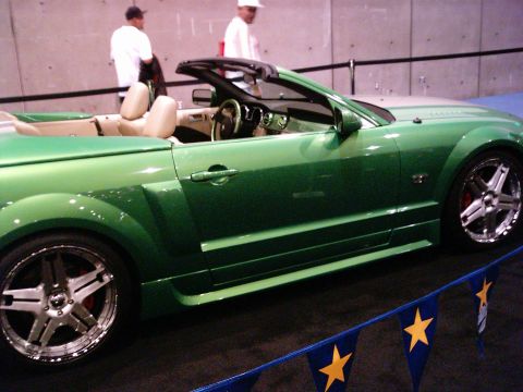 1986 Ford Bronco - Side view of a green convertible sports car, likely a Ford Mustang, on display.