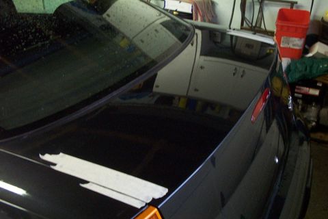 1999 Chrysler 300M - Rear view of a black car with tape on the trunk, parked in a garage.