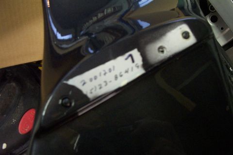 1999 Chrysler 300M - A label with handwritten numbers and a single digit is affixed to a dark-colored car part.