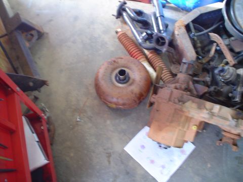 1984 Ford Bronco - Transmission and torque converter parts laid out on a garage floor.
