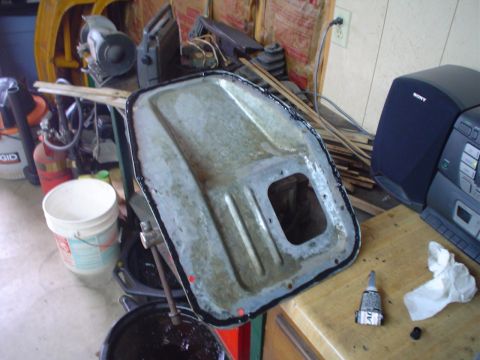 1984 Ford Bronco - A metal oil pan with sealant applied, likely for an automotive repair or maintenance task.