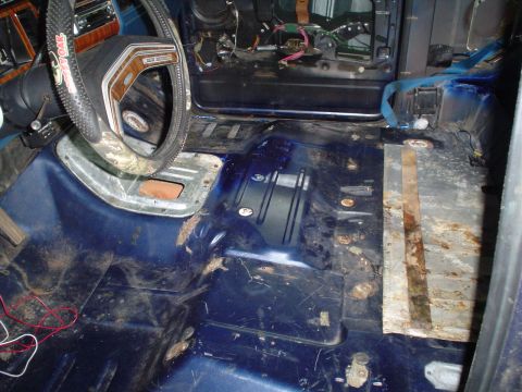 1984 Ford Bronco - The interior floor of the vehicle shows significant wear, rust, and exposed wiring, indicating a need for restoration.