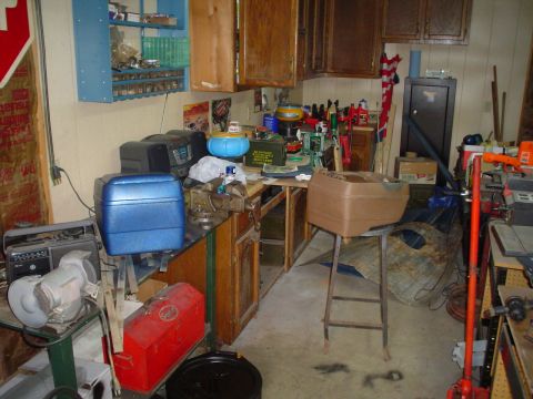 1984 Ford Bronco - A cluttered garage interior features a workbench laden with tools, storage cabinets, and various items.