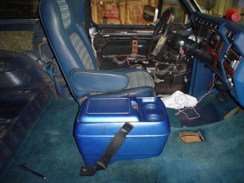 1984 Ford Bronco - The interior of a 1984 Ford Bronco features blue seats, carpeting, and a blue center console with cup holders.