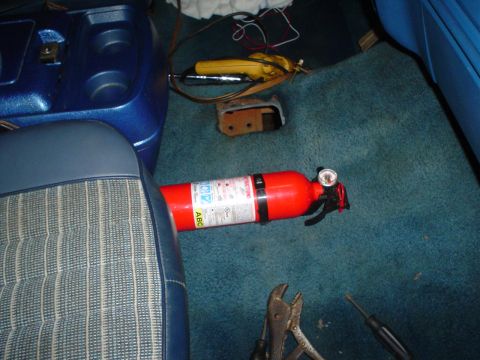 1984 Ford Bronco - Tools and a fire extinguisher are visible on the floor of a vehicle's interior.
