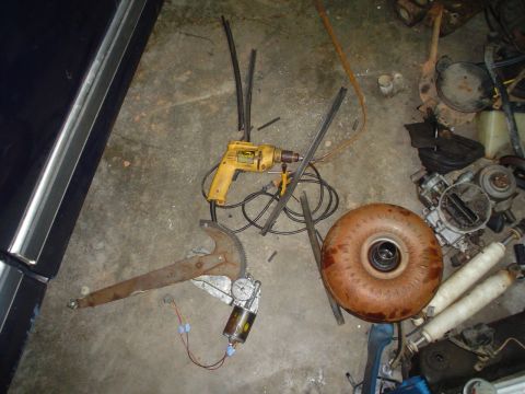 1984 Ford Bronco - Various car parts and tools are laid out on a garage floor.