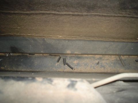 1984 Ford Bronco - This photo shows a close-up view of the underbody of a vehicle, with visible metal components and some detached wires.