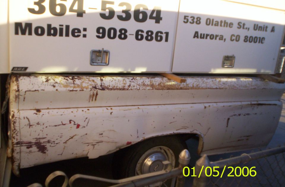 Rusty white pickup bed side view with lettered utility cap showing Aurora CO phone numbers and address