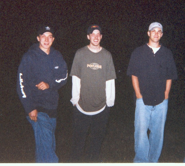 Three young men posing outdoors at night, no vehicle visible