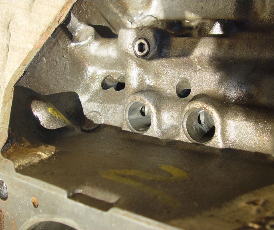 Close-up of lifter bores in a bare engine block with camshaft lobes visible