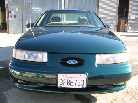 1995 Ford Taurus - Frontal view of a dark green 1995 Ford Taurus, displaying its grille and headlights.
